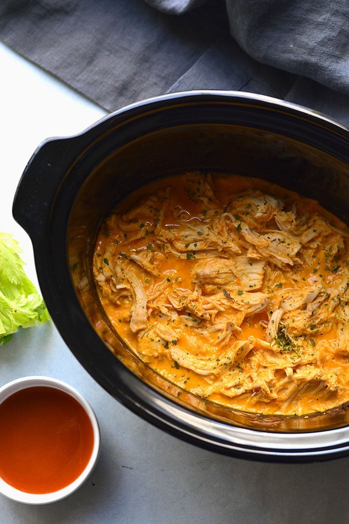 Healthy Crockpot Buffalo Chicken with just 4 ingredients! Chicken slow cooked in a secret high protein sauce make super tender and juicy shredded chicken. An easy recipe for meal prep. Low Carb + Low Calorie + Gluten Free