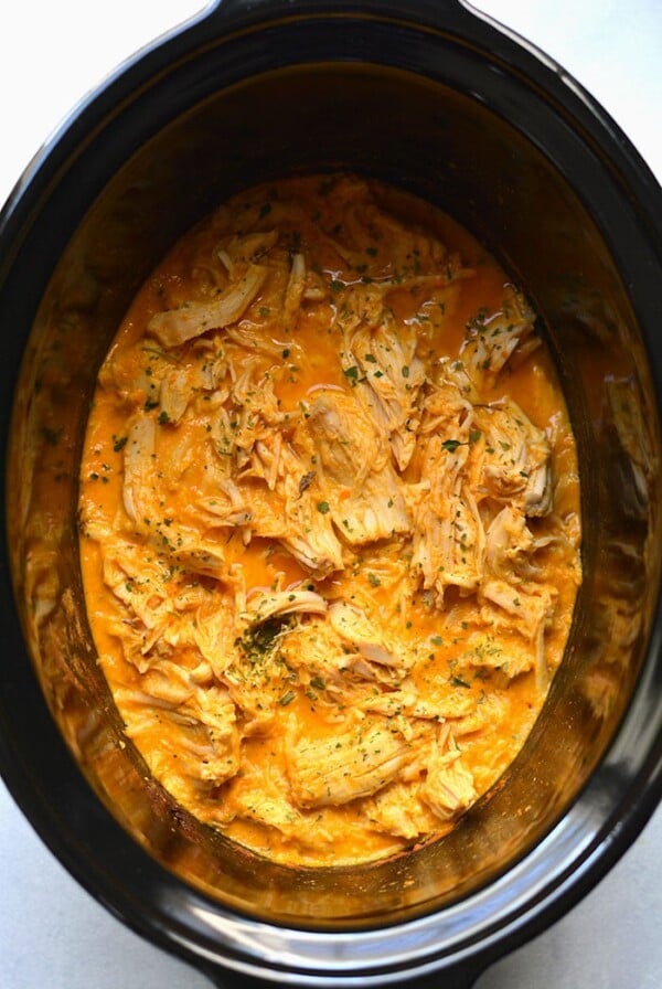Healthy Crockpot Buffalo Chicken with just 4 ingredients! Chicken slow cooked in a secret high protein sauce make super tender and juicy shredded chicken. An easy recipe for meal prep. Low Carb + Low Calorie + Gluten Free