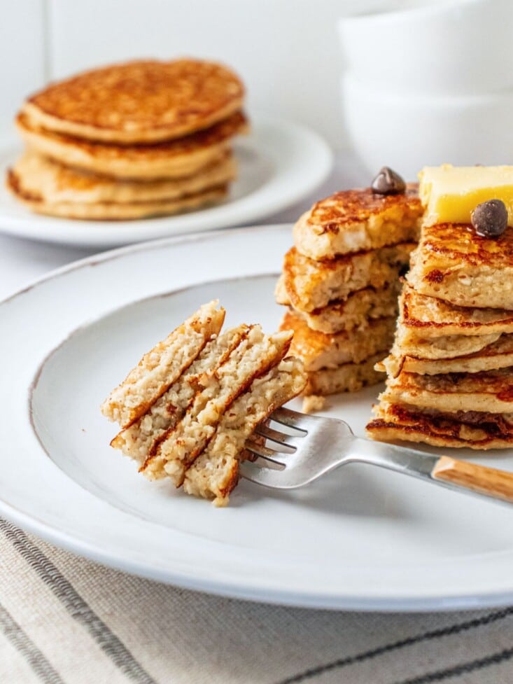 Banana oat pancakes on a plate with a portion cut out and on a fork.