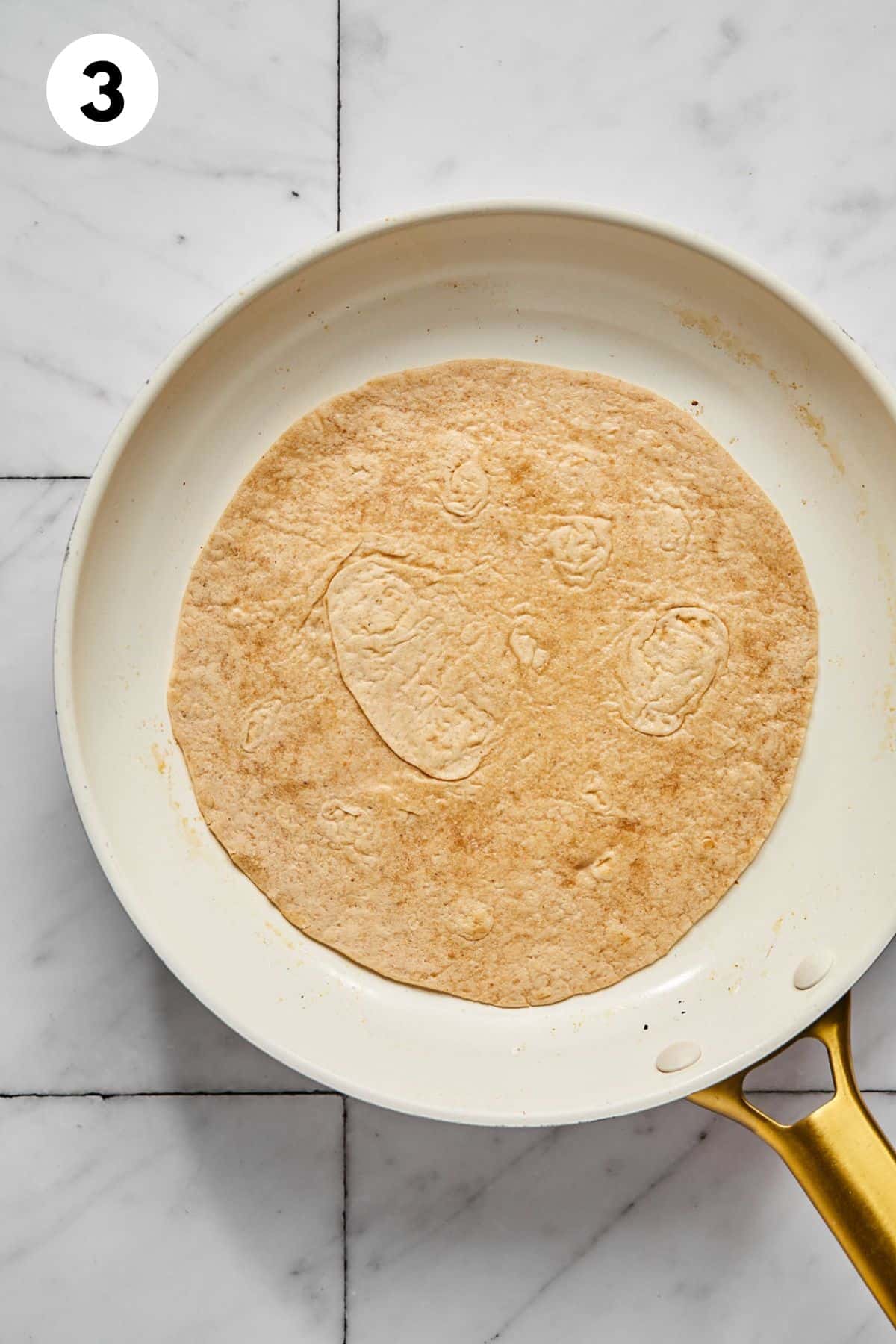 Tortilla added to a skillet.