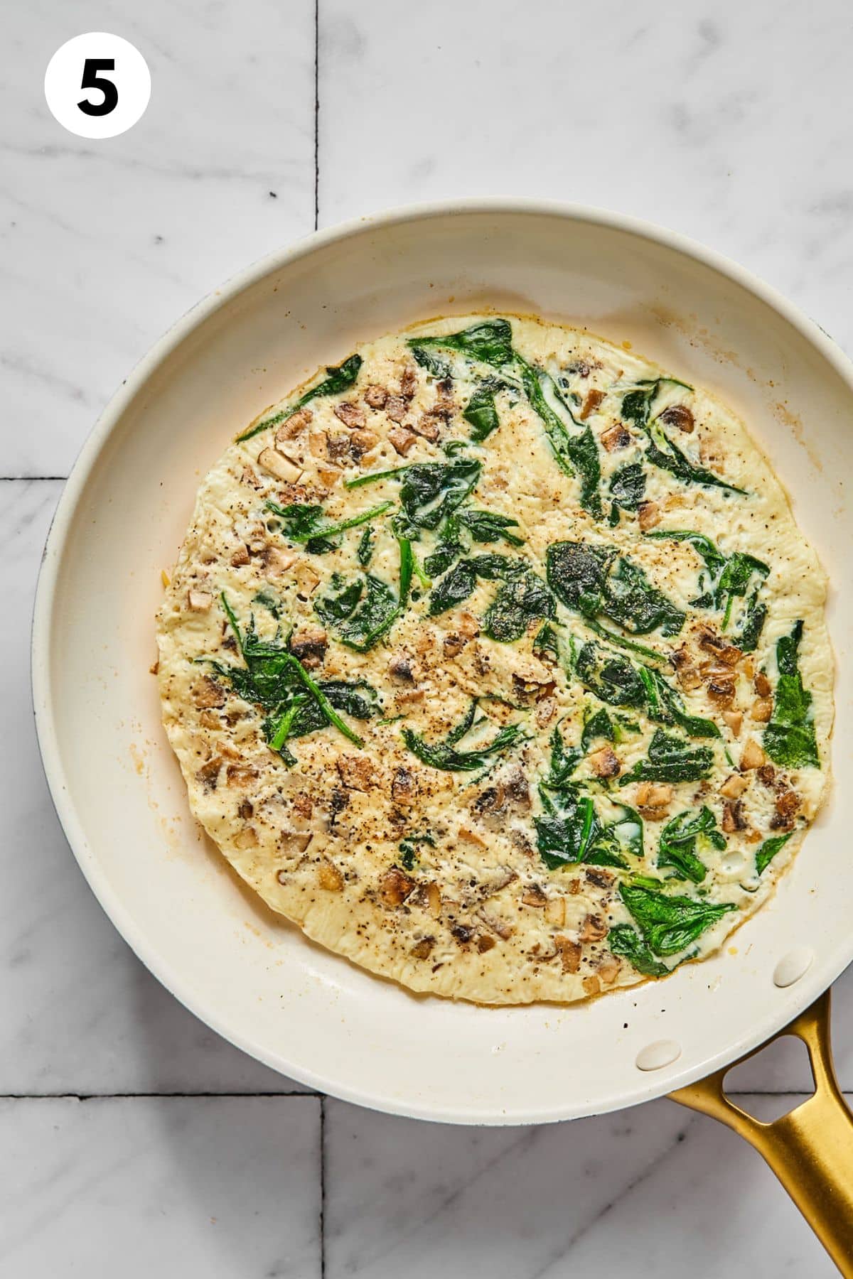 Flat egg and vegetable mixture added on top of the cheese.