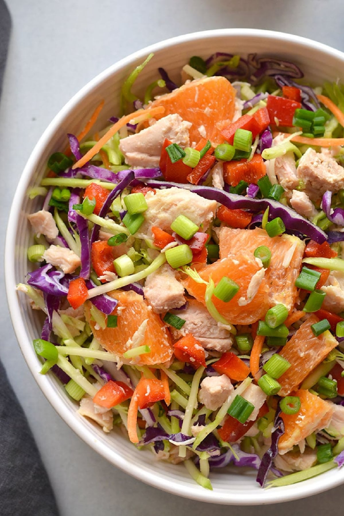 Chinese chicken salad with oranges and dressing in a white bowl.