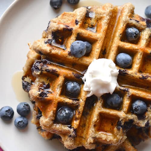 waffle with blueberries and whipped cream on top.