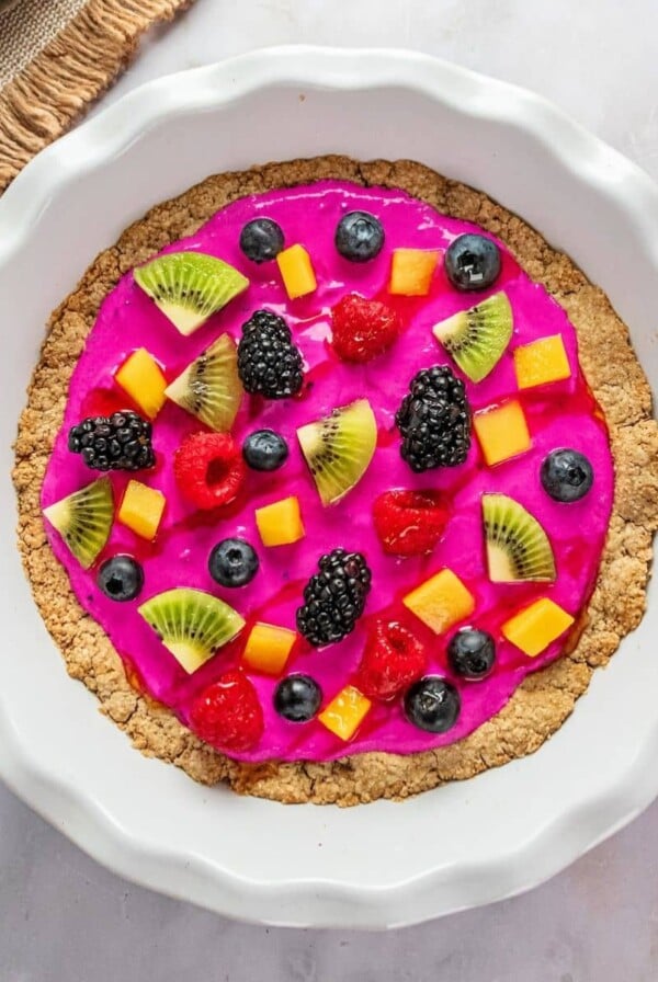 Healthy fruit pizza in a white pie dish on a table.