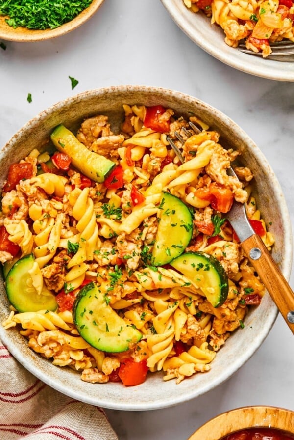 A skillet of taco pasta with a wooden utensil resting on the side.