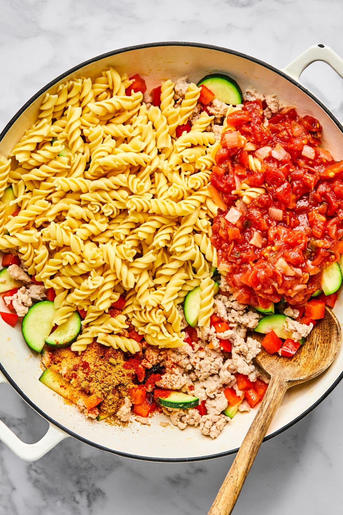 Pasta and seasonings added to the skillet of cooked chicken and vegetables.