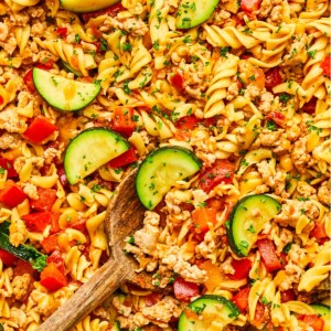 Taco pasta loaded with vegetables and a wooden spoon resting in the dish.