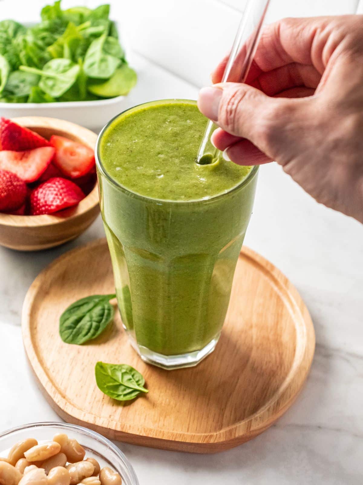 A hand adding a straw to a glass of a high protein high fiber smoothie.