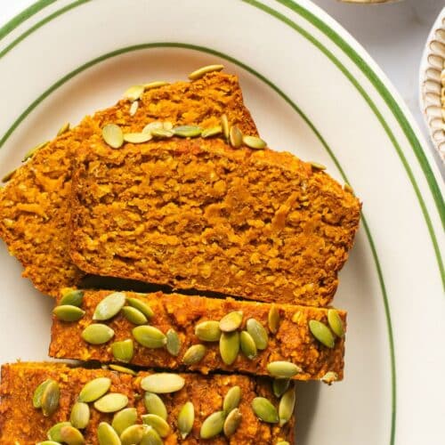 Slices of pumpkin oatmeal bread on a plate with some laying on their side.