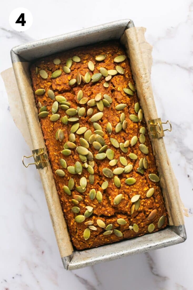 Baked pumpkin oatmeal loaf in a pan topped with pumpkin seeds.