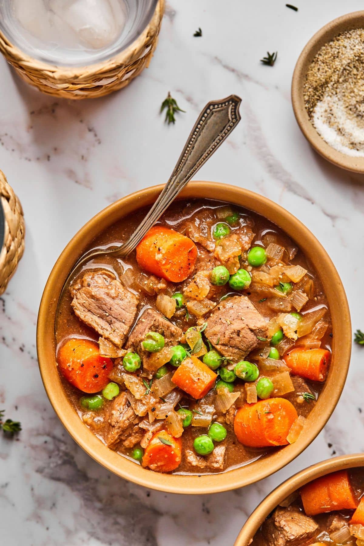 A bowl of healthy beef stew in a crockpot on the table with a spoon in the bowl.