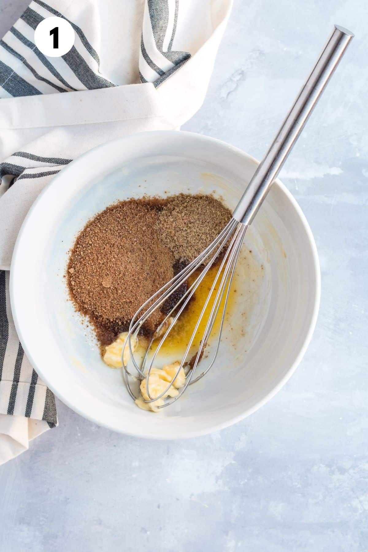 Butter and sugar in a mixing bowl with a whisk.