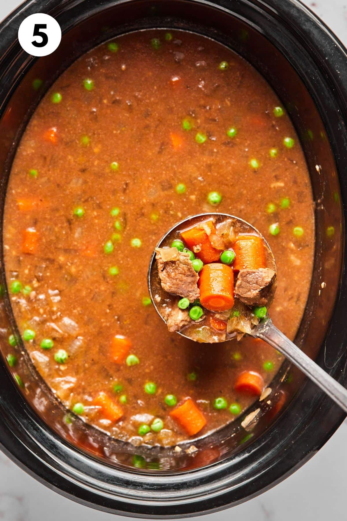 A ladle lifting a bit of the healthy beef stew from the crockpot.