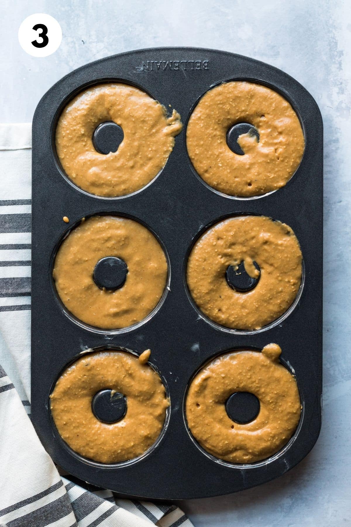 Donut batter added to a donut pan.