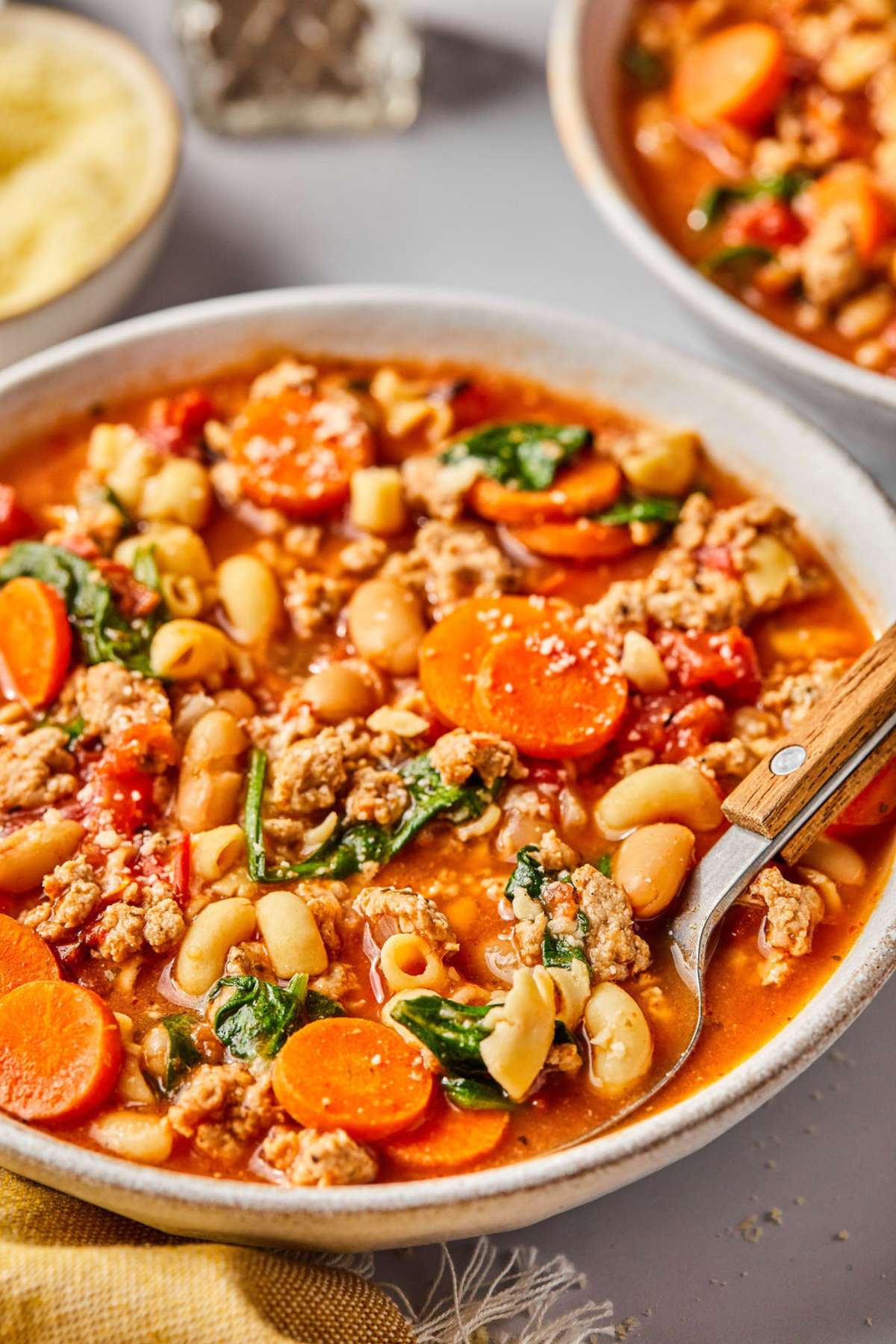 A bowl of healthy pasta e fagioli on the table with a spoon in the bowl.