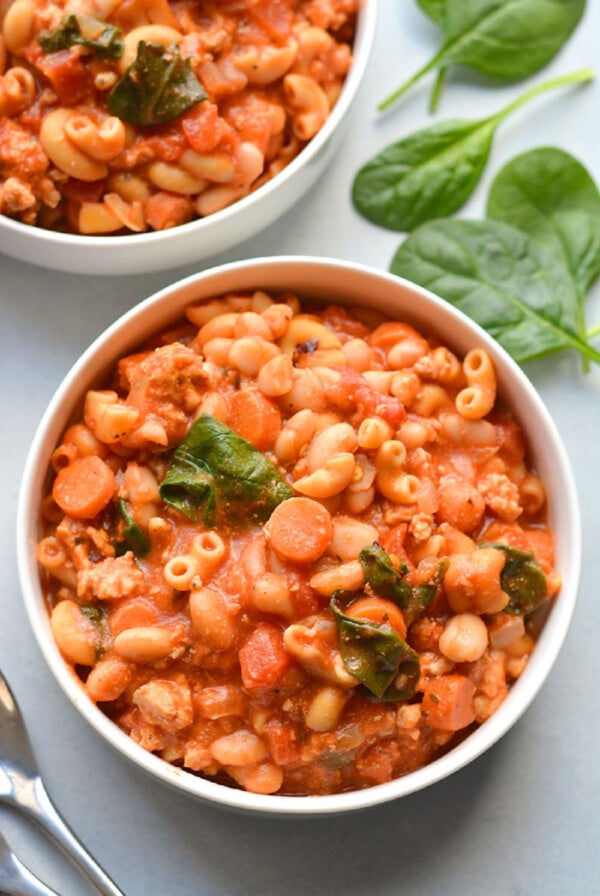 Pasta fagioli in a white bowl on a table.