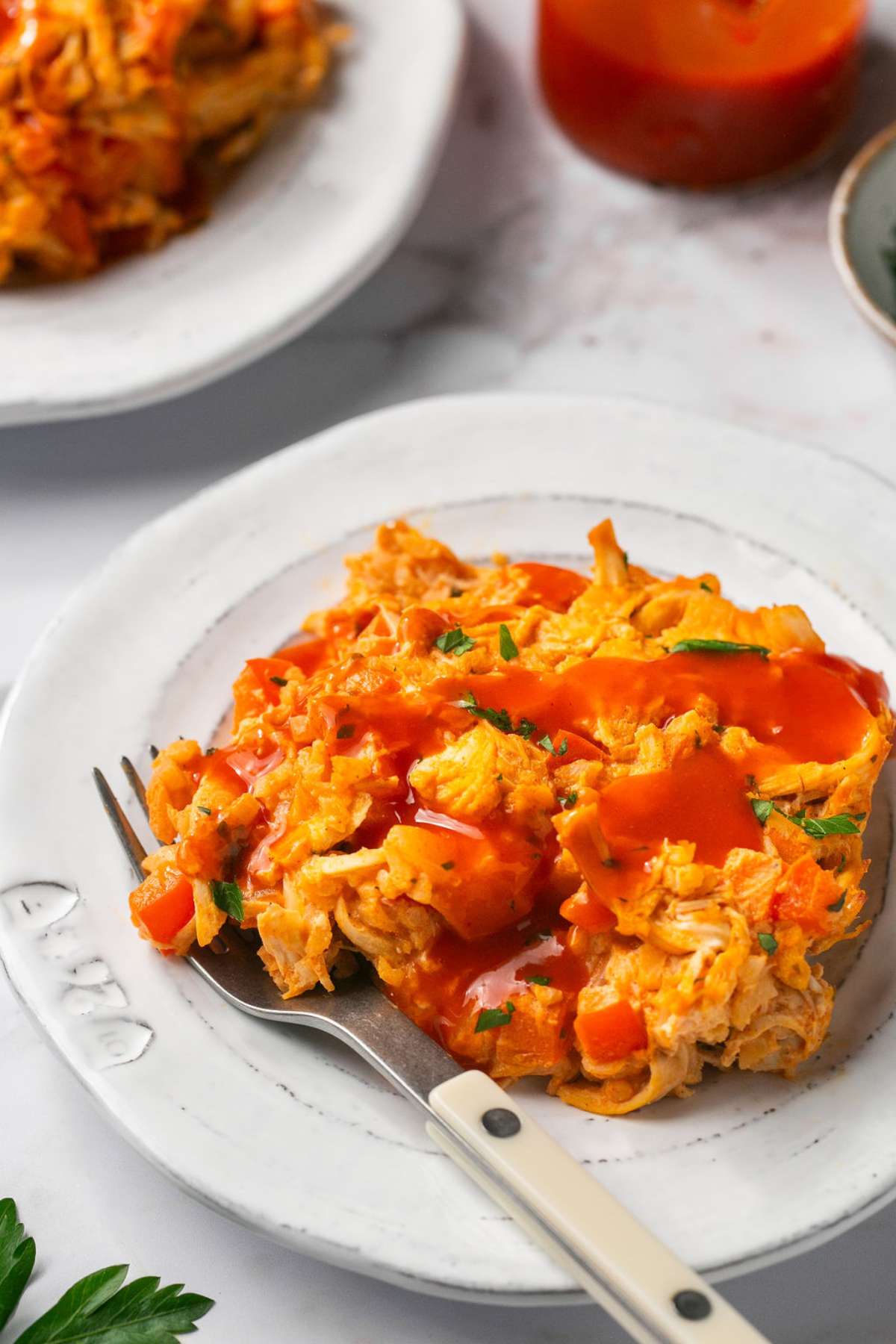 A plate of buffalo chicken casserole with buffalo sauce drizzled over the top.