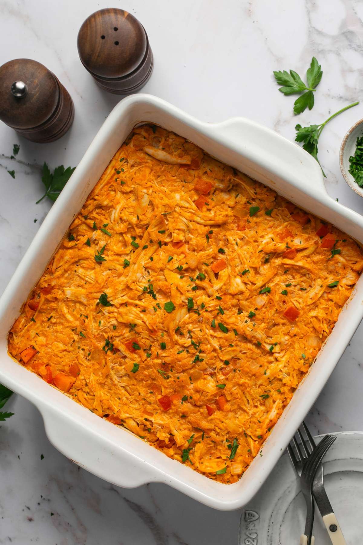 Healthy buffalo chicken casserole in a baking dish garnished with parsley.