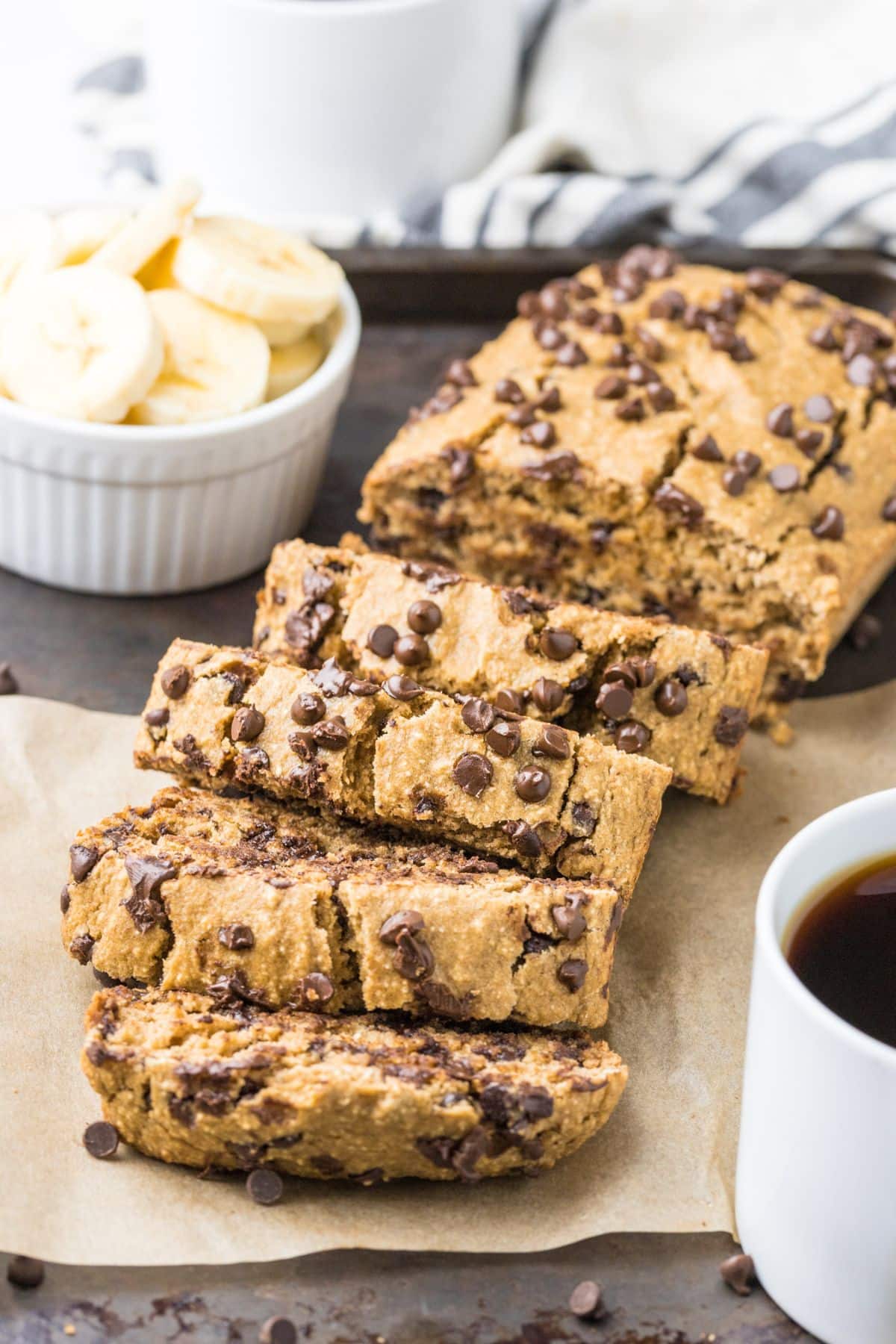 A loaf of banana oat bread sliced on a baking pan and the pieces laying over on their side.