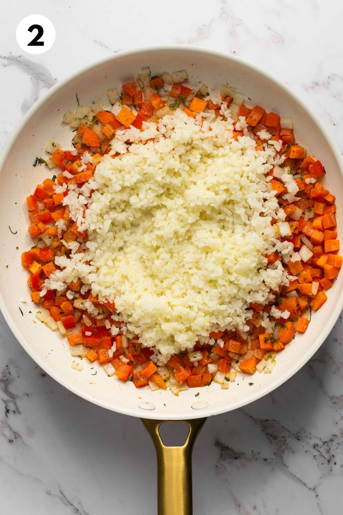 Cauliflower rice added to cooked vegetables in the skillet.