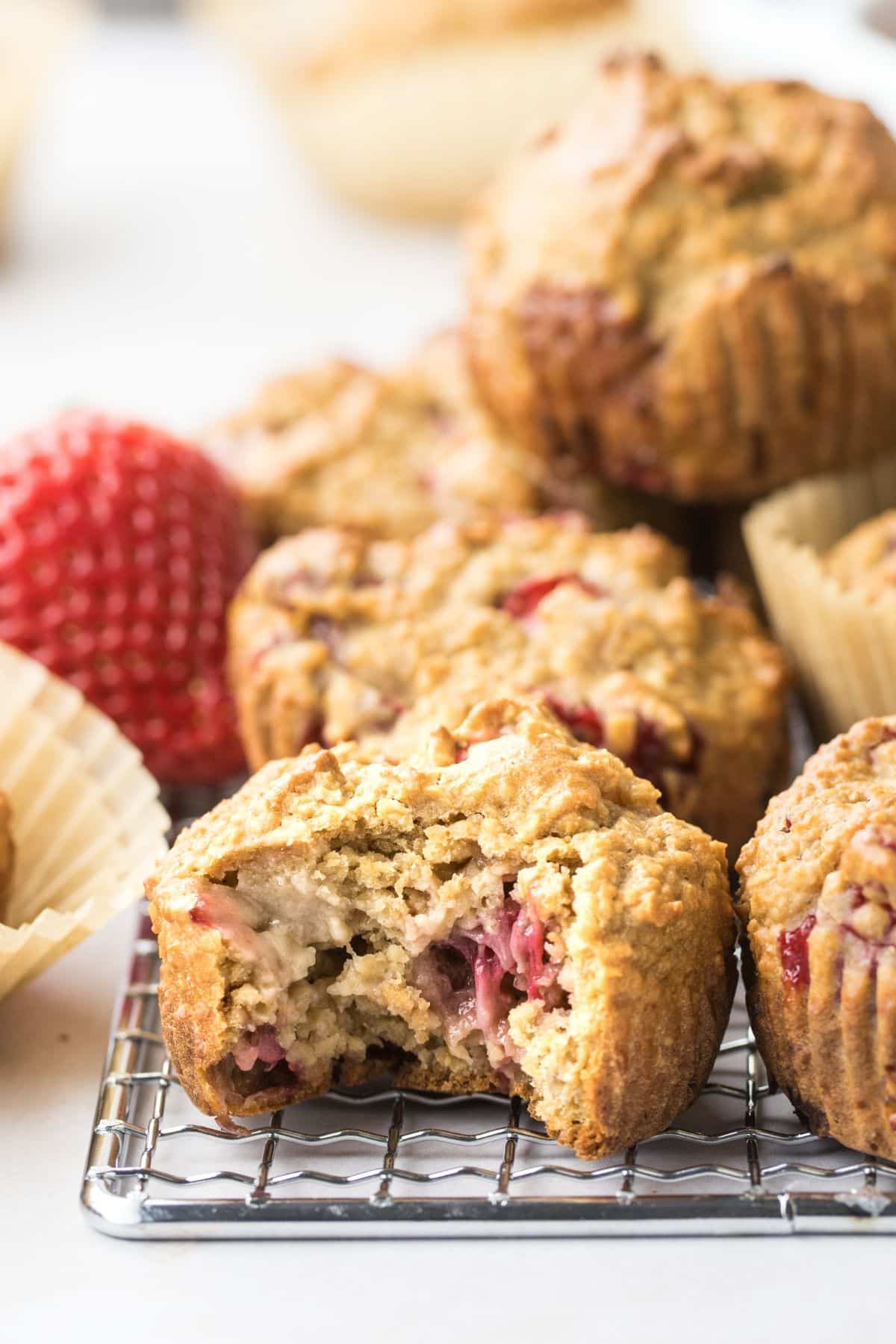 A pile of strawberry protein muffins with one that has a bite taken out.