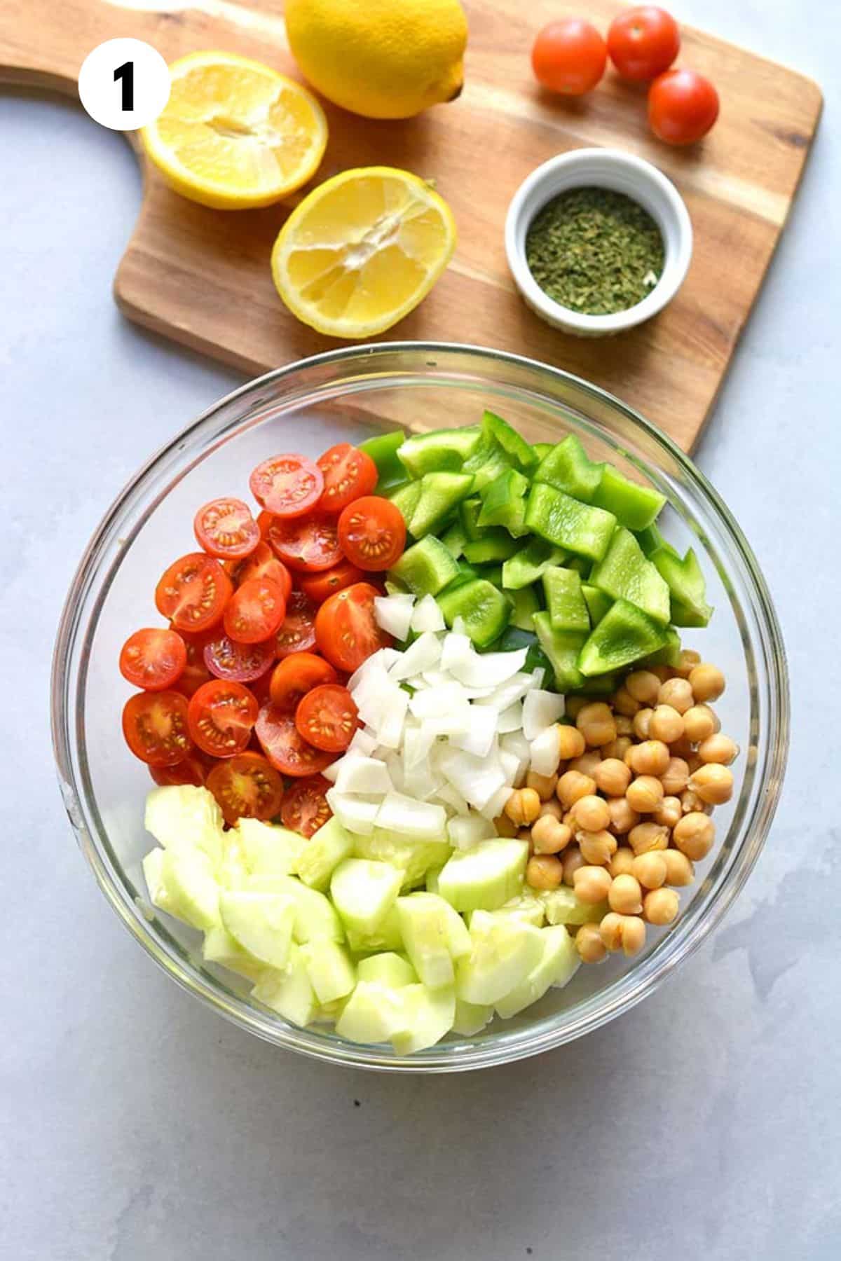 Vegetables and chickpeas added to a bowl with a lemon and parsley to the side.