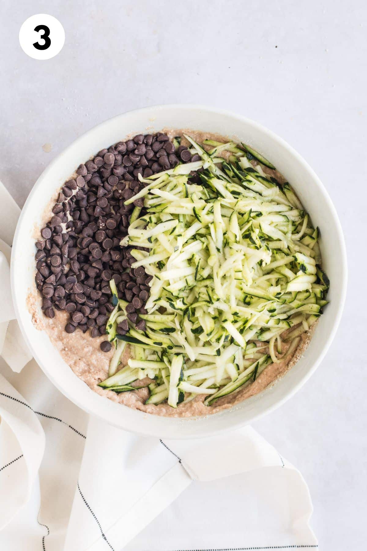 Shredded zucchini and chocolate chips added to the bowl.
