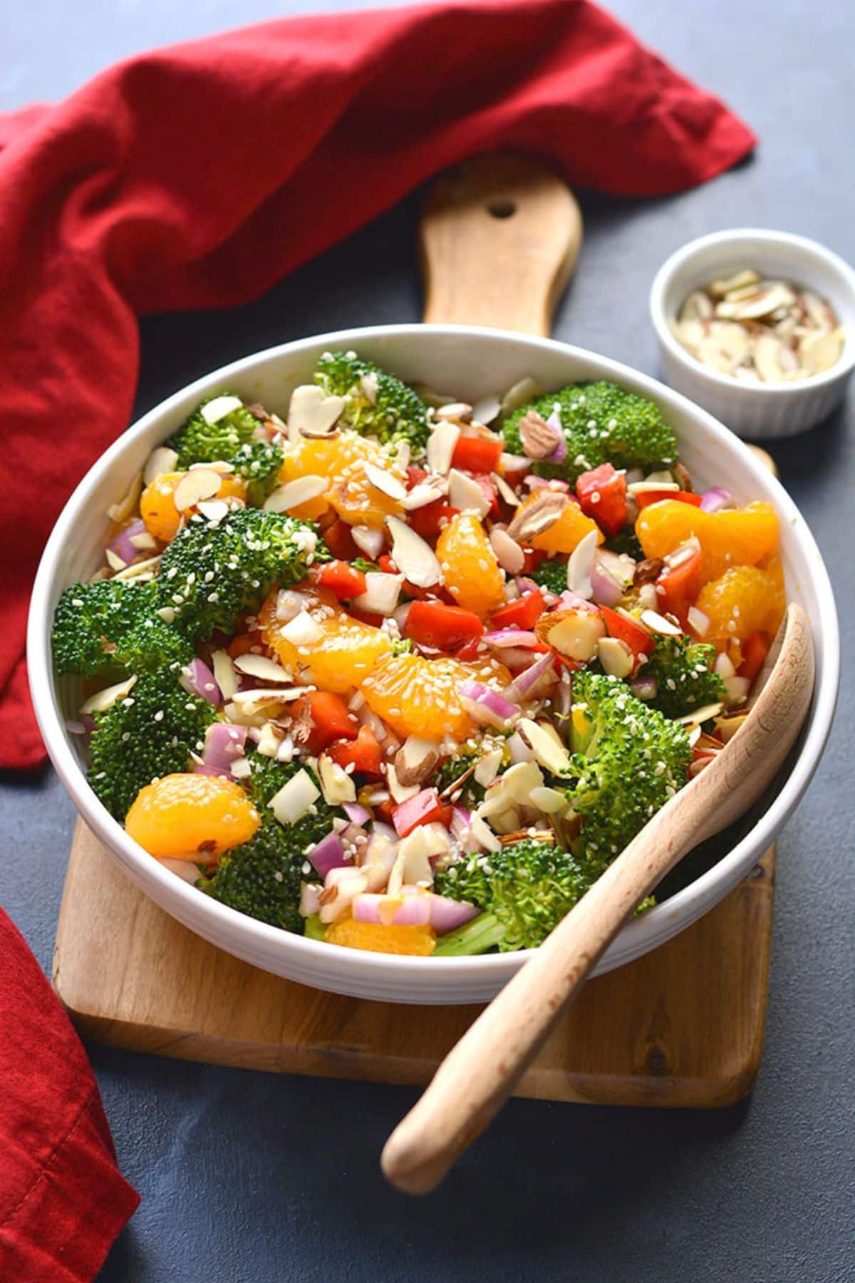 A bowl of Asian broccoli salad with a wooden spoon resting in the bowl. 