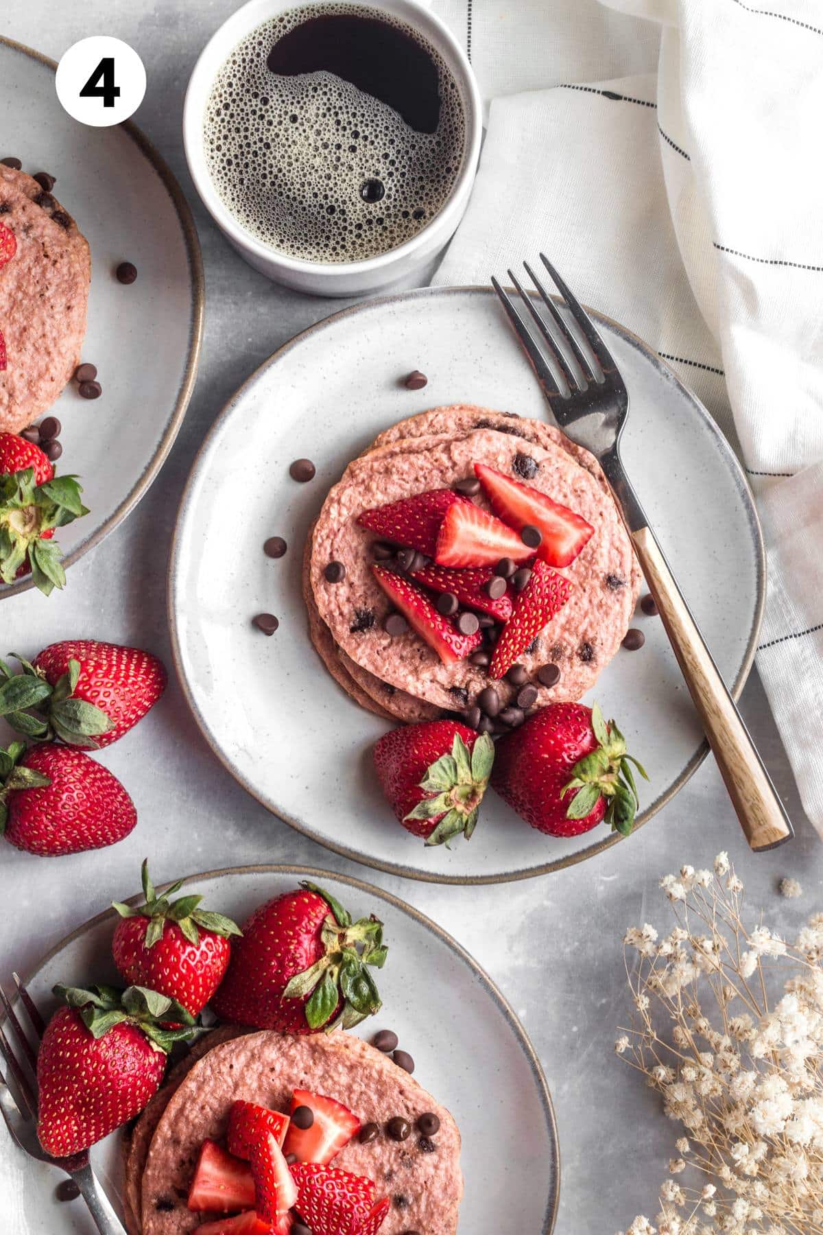 Chocolate chip strawberry pancakes served up on plates on a table.