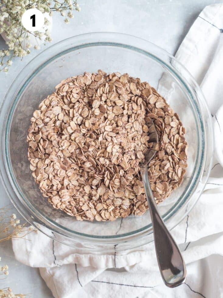 Oatmeal added to a mixing bowl with a spoon resting in the dish.