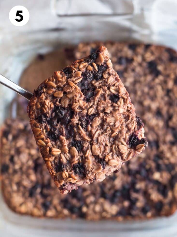 A portion of baked blueberry oatmeal held up over the baking dish with more in it.