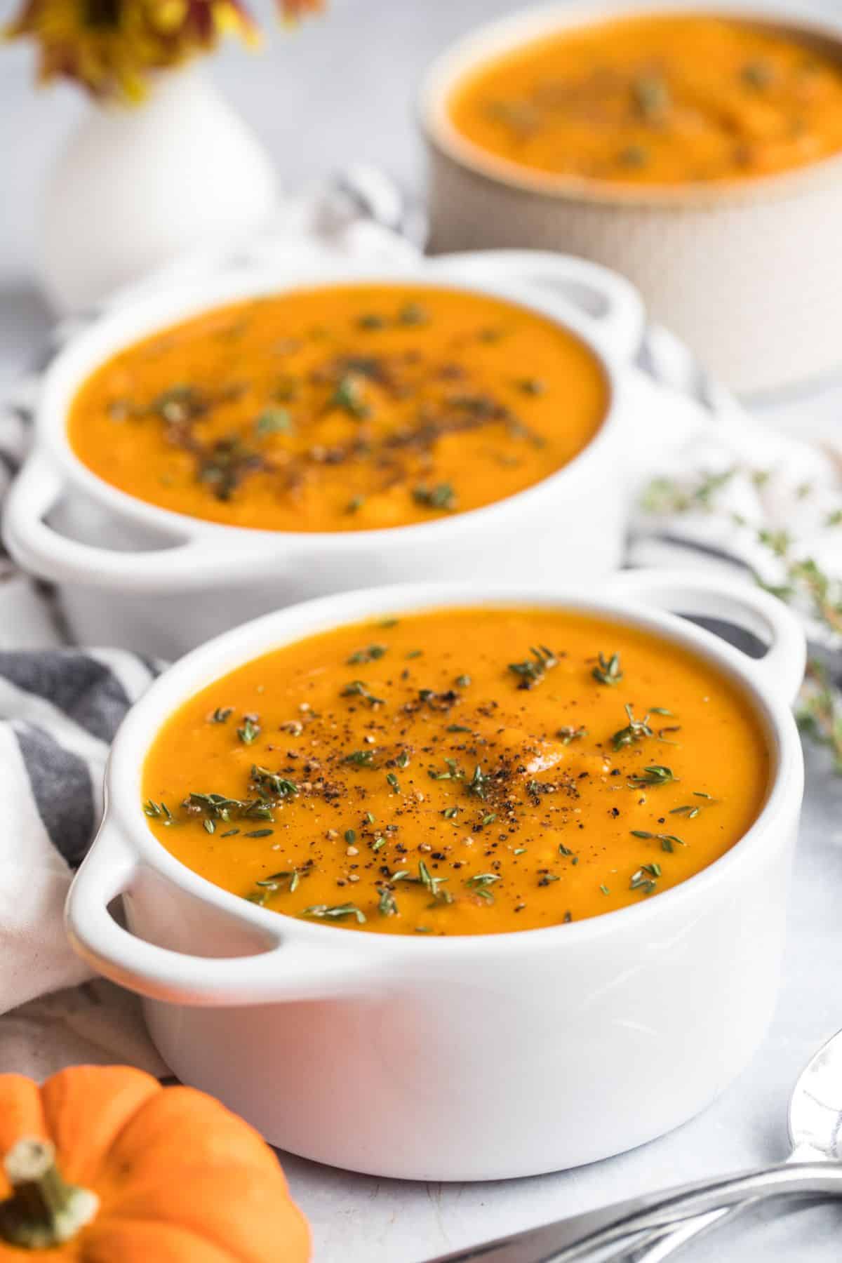 Two bowls of butternut squash and sweet potato soup.