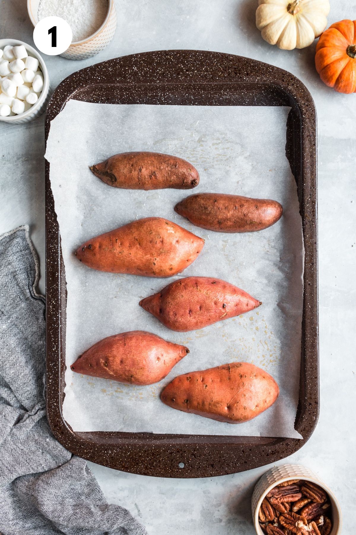 Whole sweet potatoes on a baking sheet.