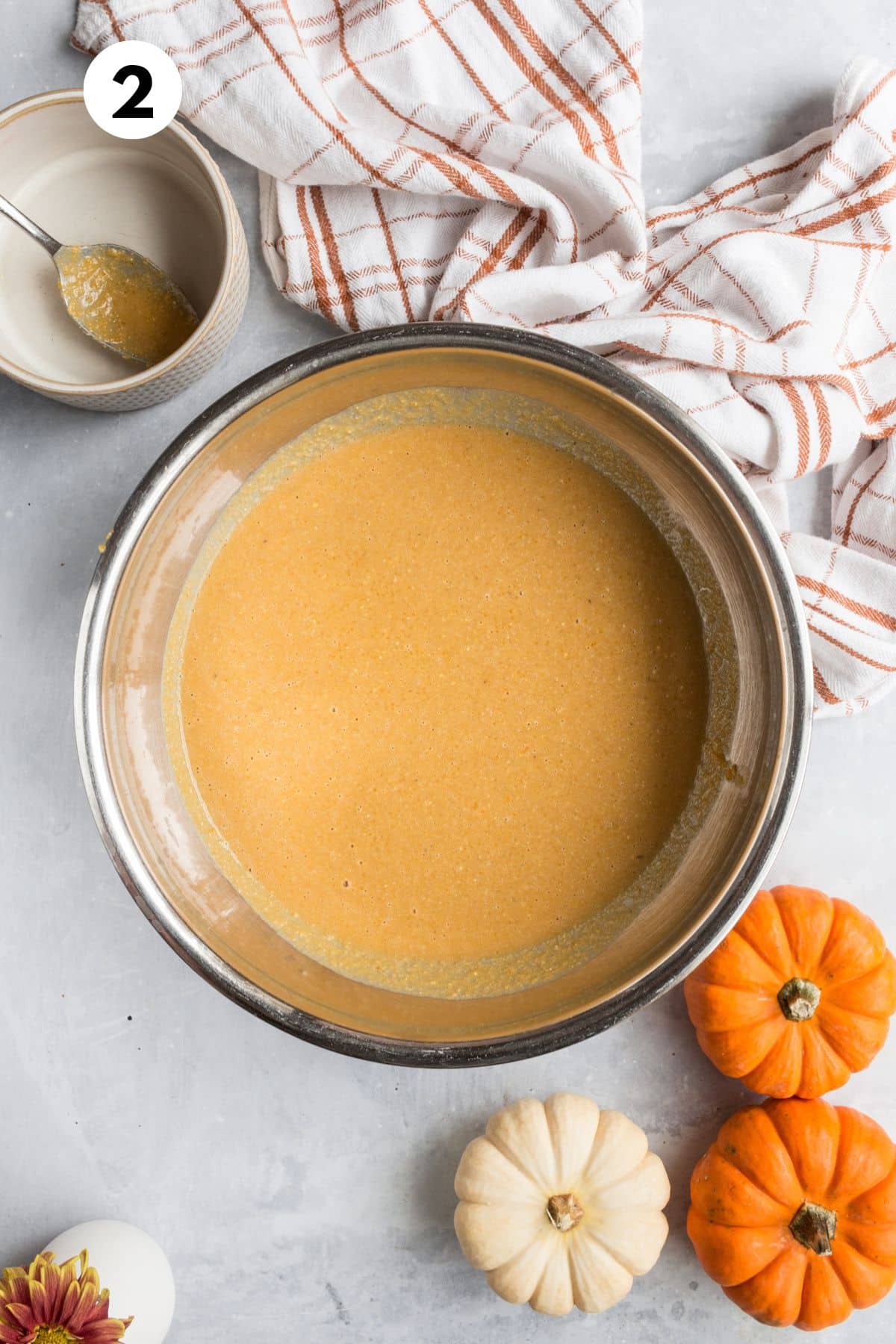 Ingredients for making pumpkin muffins blended together in a mixing bowl.
