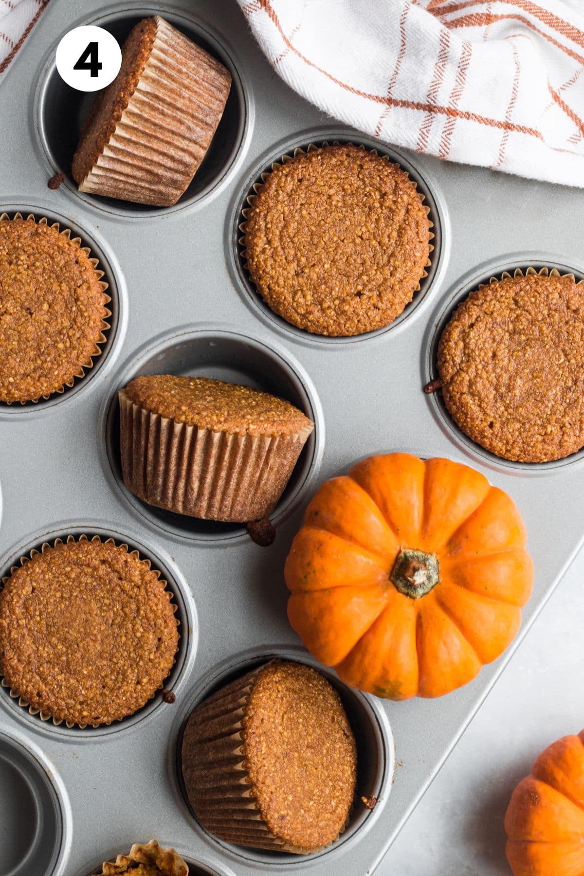 Baked pumpkin cornbread muffins in a muffin tin.