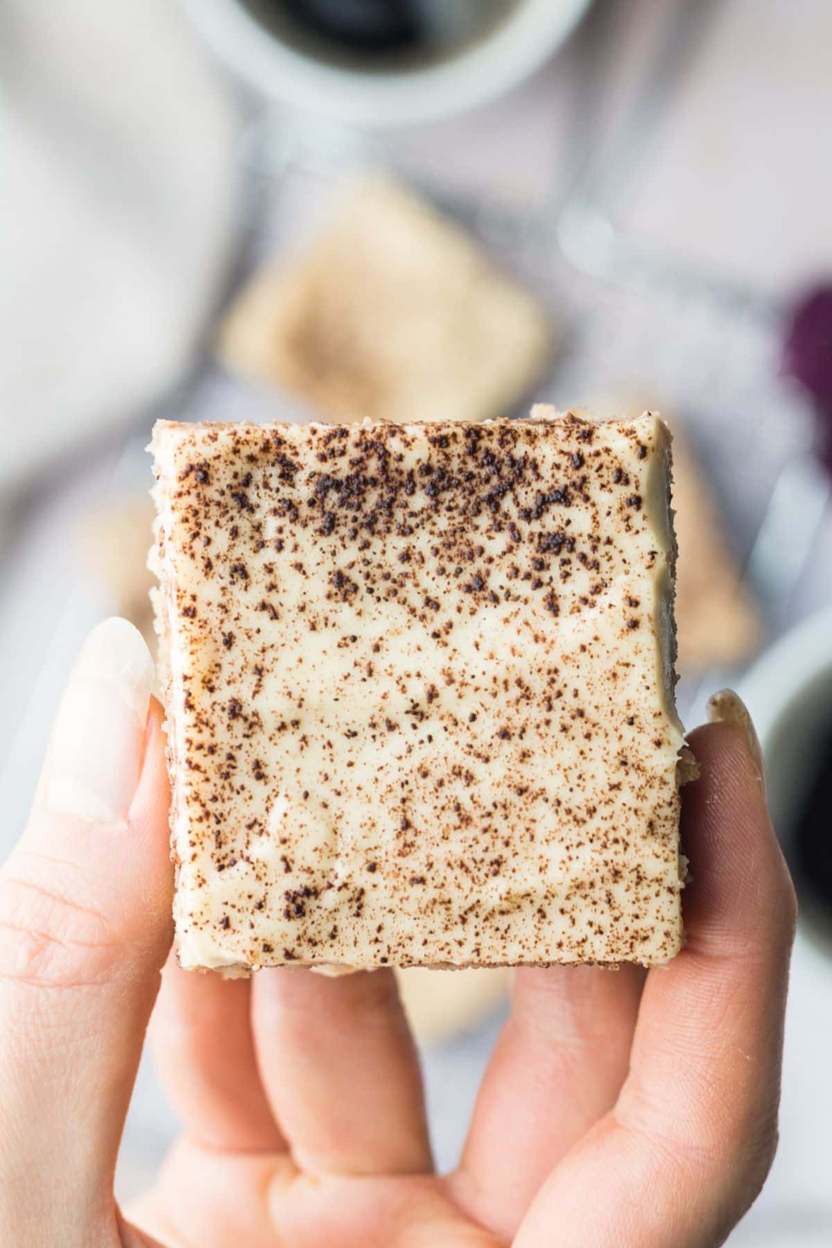A hand holding a piece of gluten free gingerbread cake.