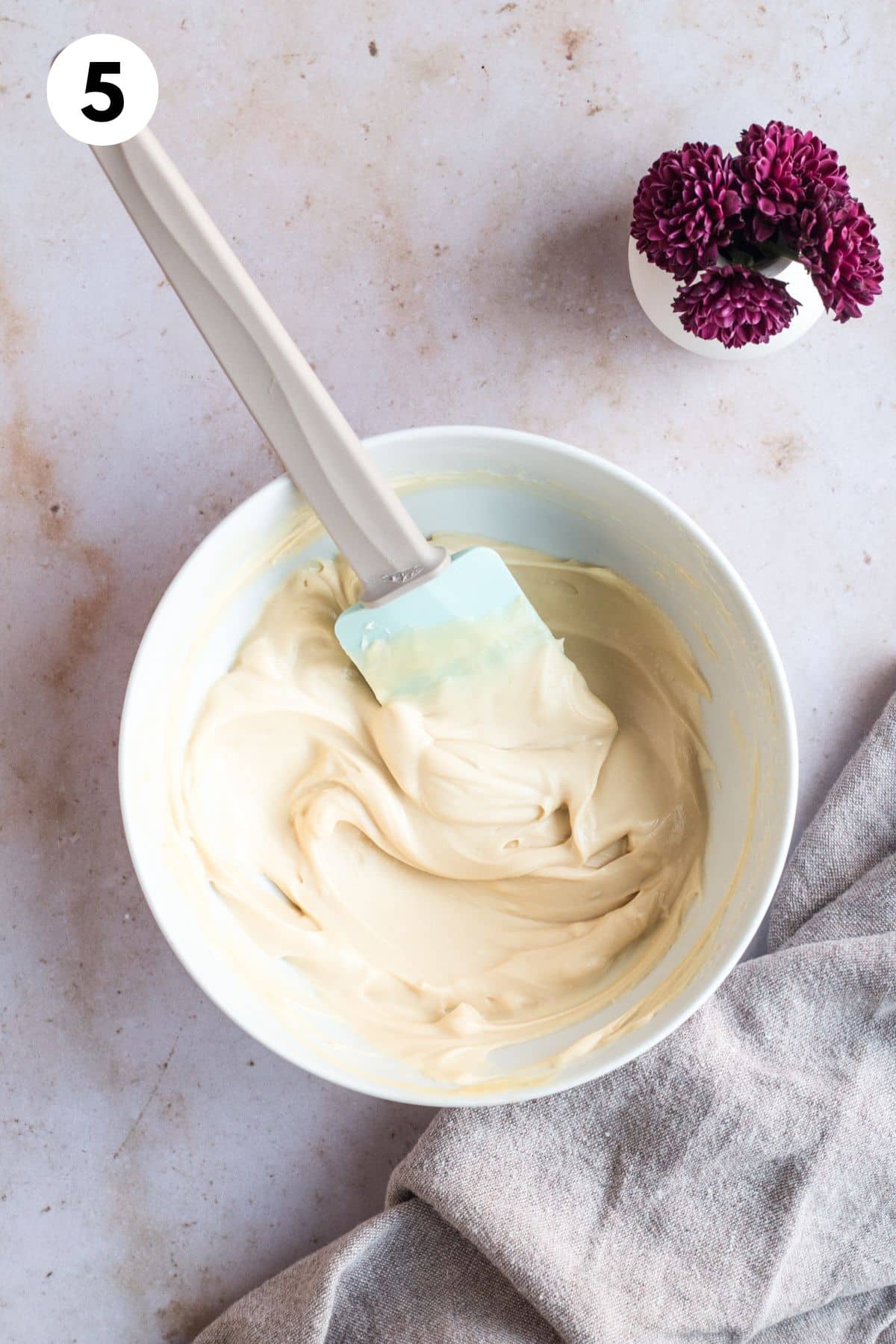 Gingerbread cake frosting in a mixing bowl with a spatula.