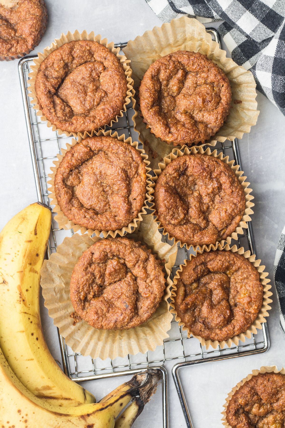 Banana muffins with almond flour on a cooling rack with a fresh banana.