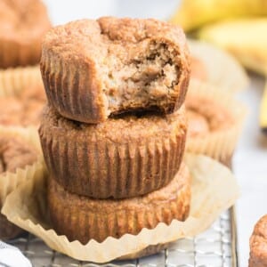A stack of three banana muffins with almond flour and one on top with a bite missing.