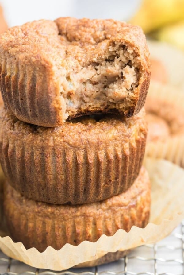A stack of three banana muffins with almond flour and one on top with a bite missing.