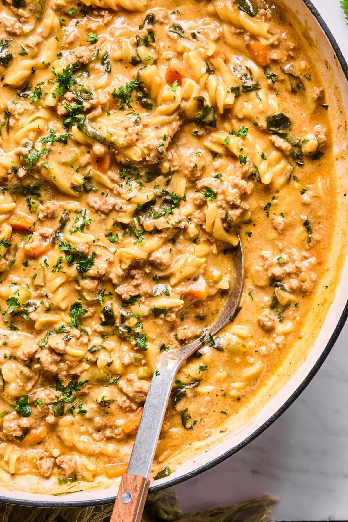 A pot of healthy hamburger helper with a spoon lifting up a portion.