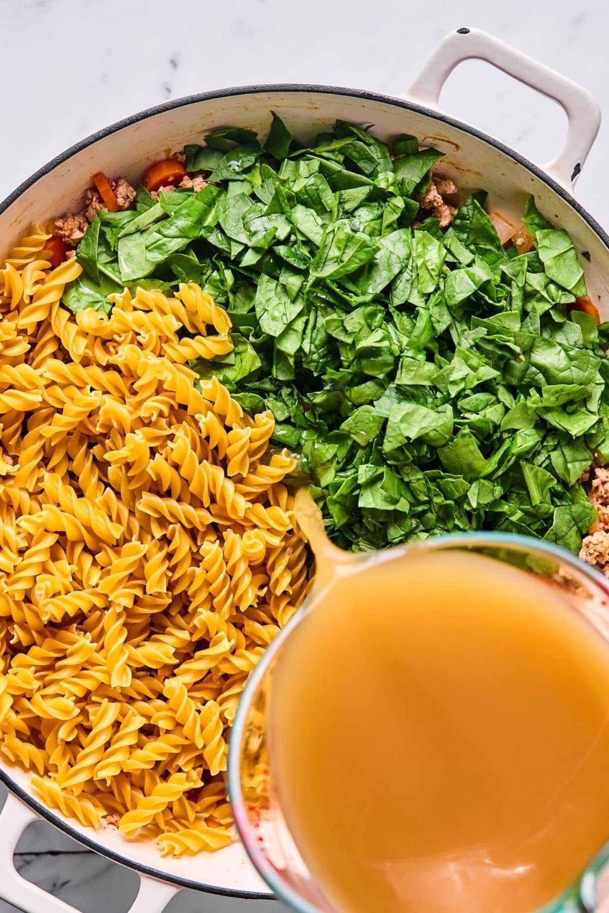 Broth, spinach and pasta added to the rest of the ingredients in the pot.
