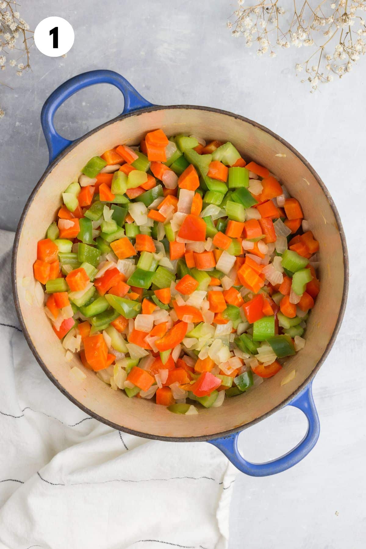 Carrots, celery, and onions added to a large pot. 