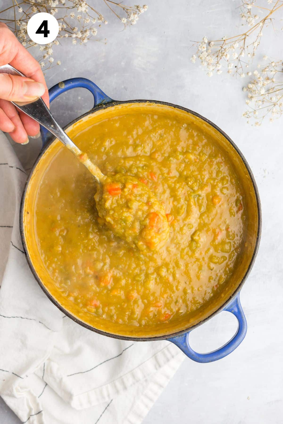 Vegan split pea soup after cooking and a hand holding a spoonful from the pot.