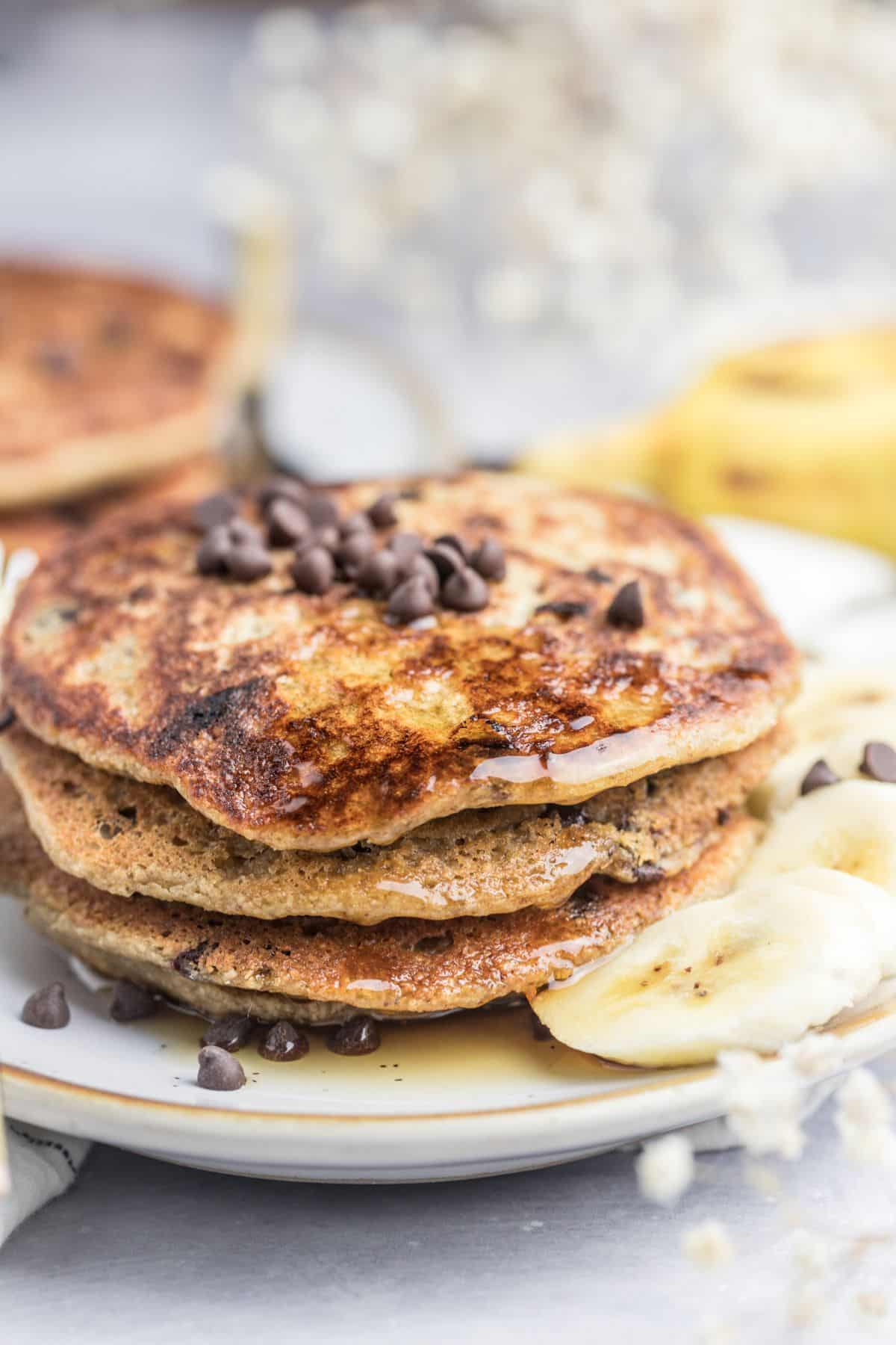 A stack of banana chocolate chip pancakes with chips and sliced bananas to garnish.