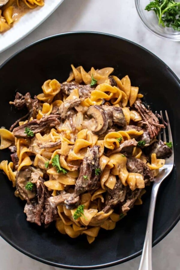 Healthy beef stroganoff in a bowl with a fork to the side.