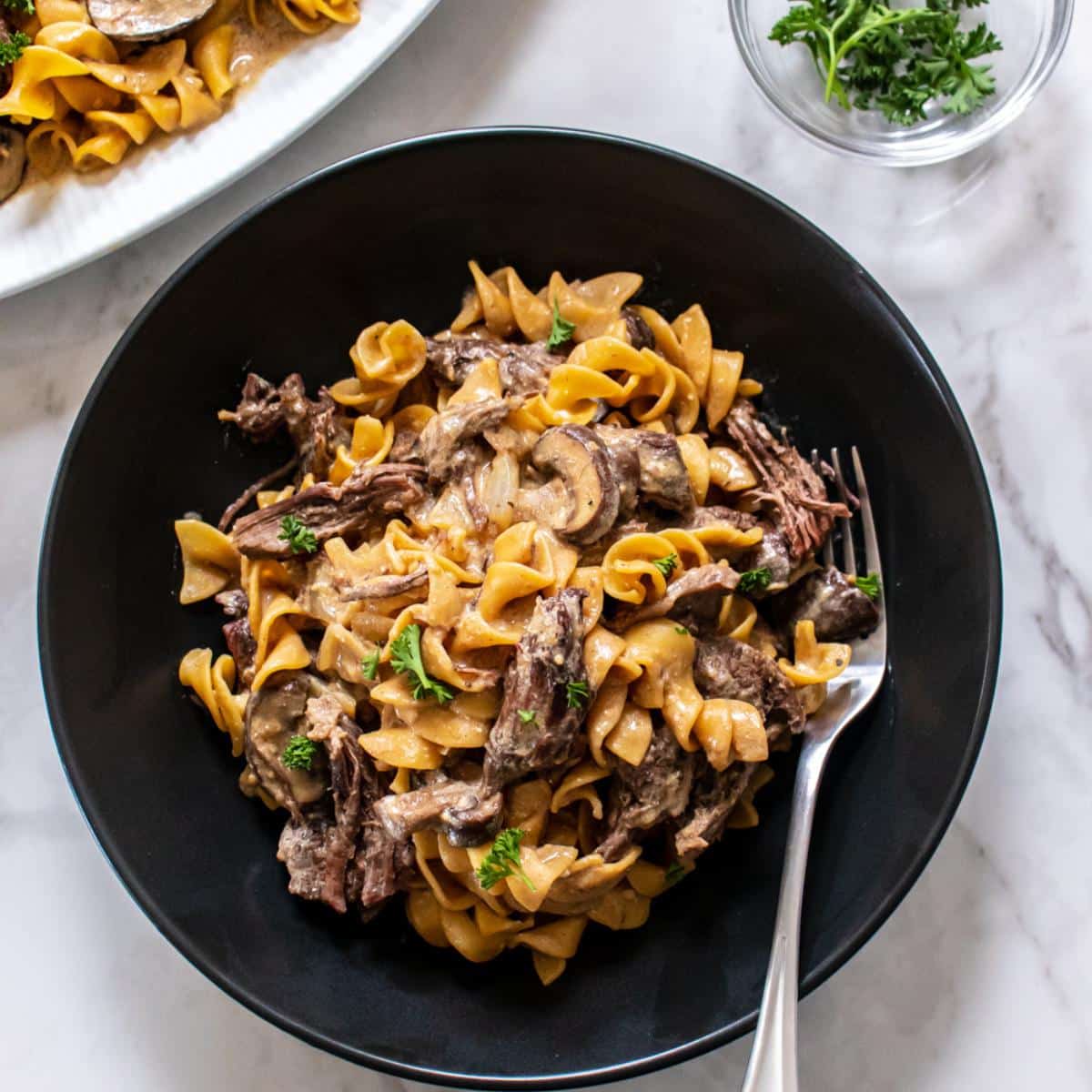 Healthy beef stroganoff in a bowl with a fork to the side.