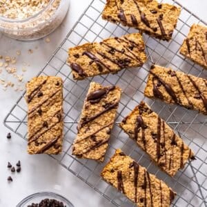 Protein granola bars on a wire rack drizzled with chocolate.