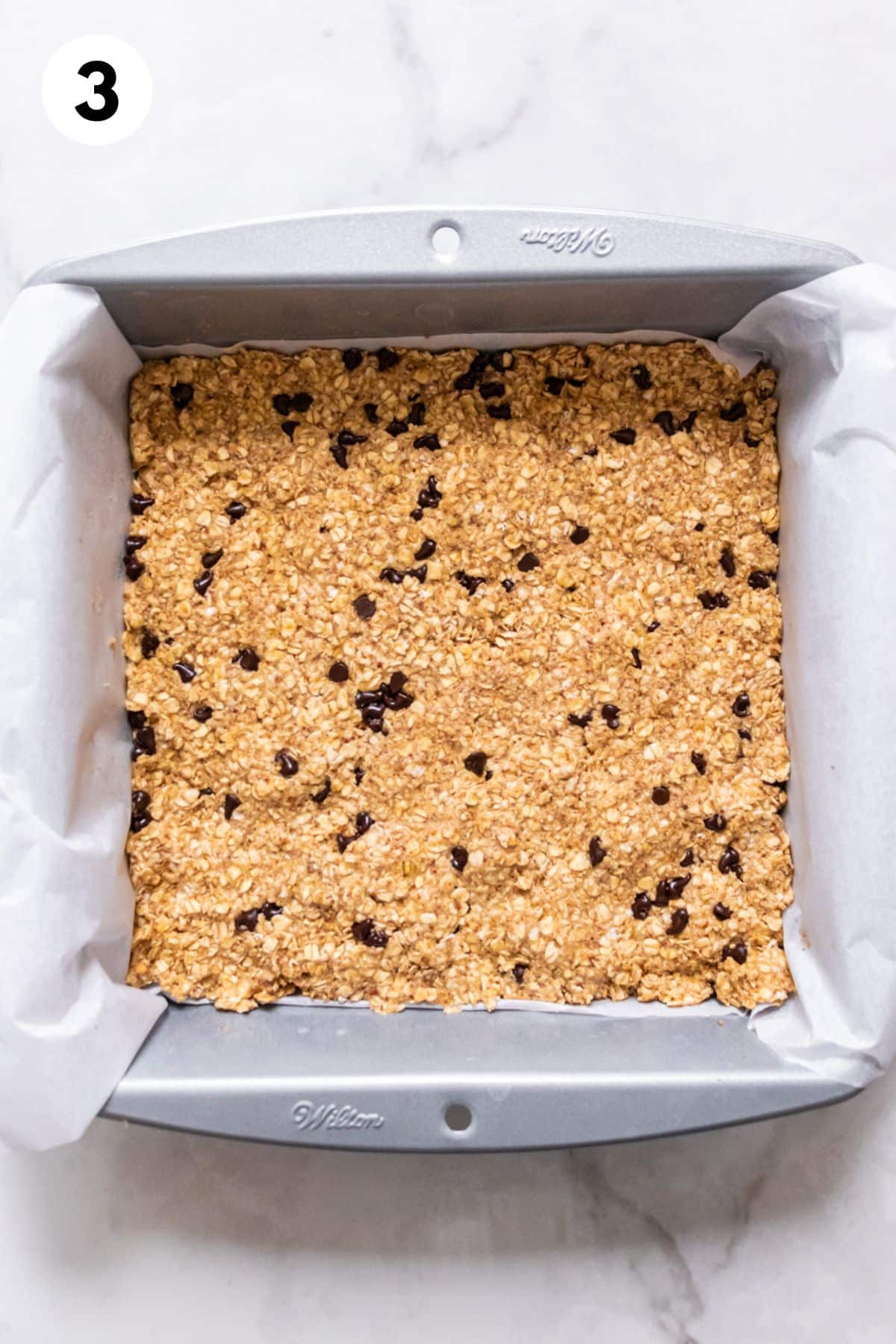 Mixture to make protein breakfast bars pressed into a square pan.