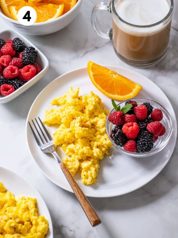 A plate of Greek yogurt scrambled eggs on the table with a fork to the side.